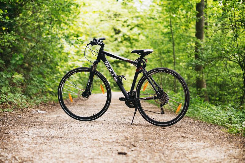 Vélo garé avec béquille sur un chemin de forêt